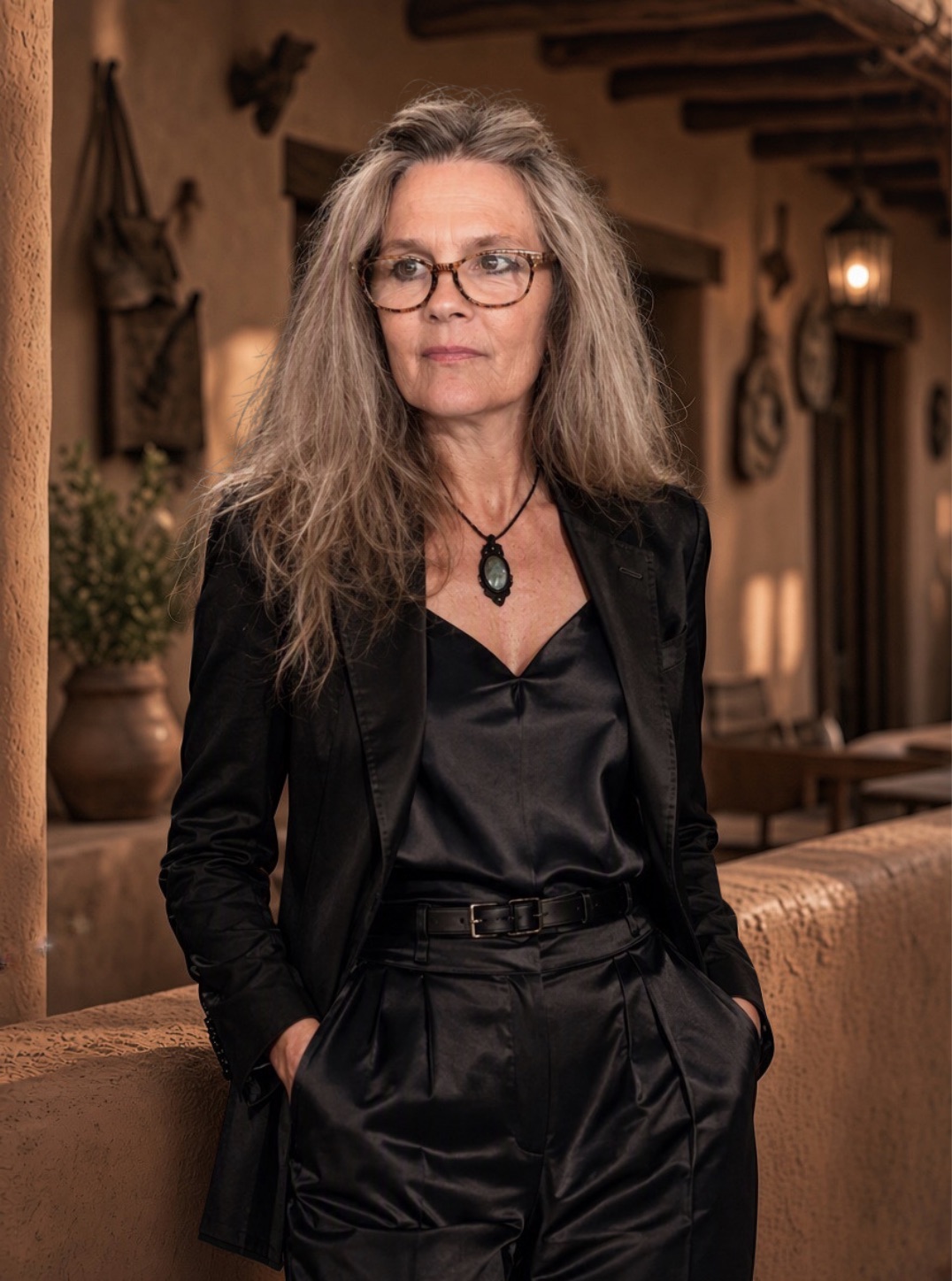 Portrait of Ana Cortez in black, standing on an adobe portico at dusk